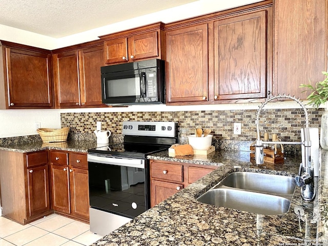 kitchen with a textured ceiling, decorative backsplash, stainless steel range with electric cooktop, and dark stone counters