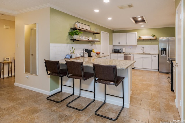 kitchen with sink, light stone countertops, white cabinetry, a breakfast bar area, and stainless steel appliances