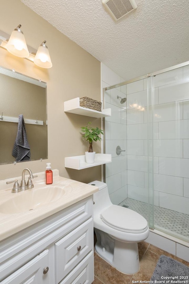 bathroom with vanity, a textured ceiling, a shower with door, tile patterned flooring, and toilet