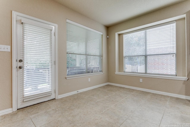 spare room featuring a healthy amount of sunlight and light tile patterned flooring