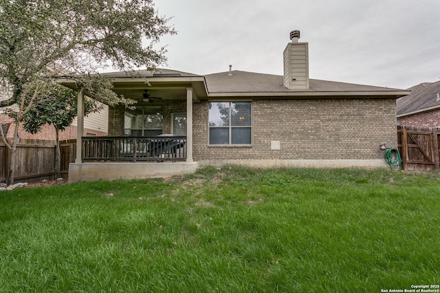 rear view of house featuring ceiling fan and a lawn