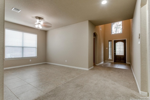 tiled entryway with a textured ceiling and ceiling fan