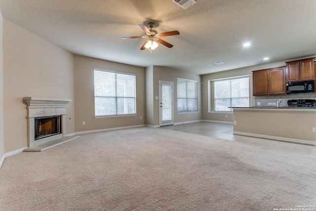 unfurnished living room with ceiling fan, light colored carpet, and a textured ceiling