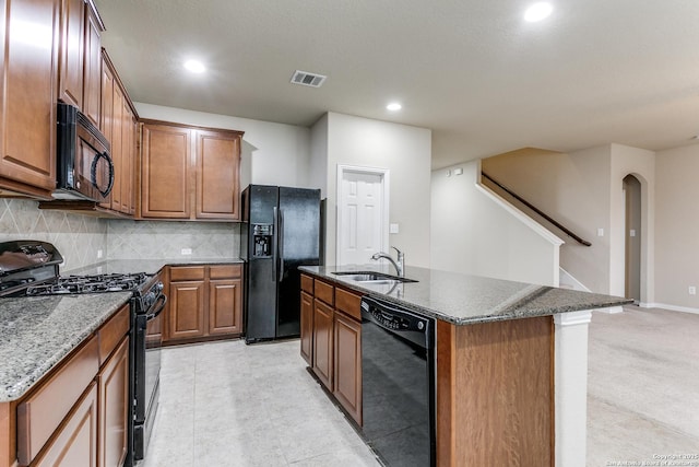 kitchen with black appliances, sink, an island with sink, and tasteful backsplash