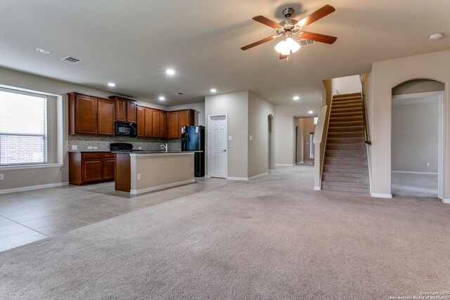 kitchen featuring backsplash, ceiling fan, black appliances, light tile patterned floors, and a center island