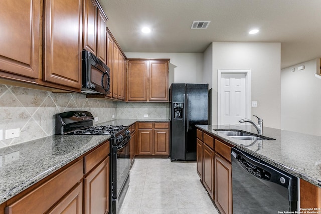 kitchen with black appliances, light stone countertops, sink, and tasteful backsplash