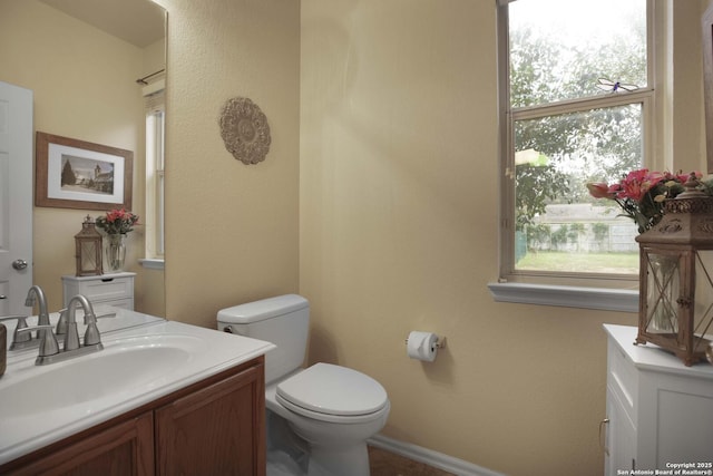 bathroom featuring vanity, a healthy amount of sunlight, and toilet