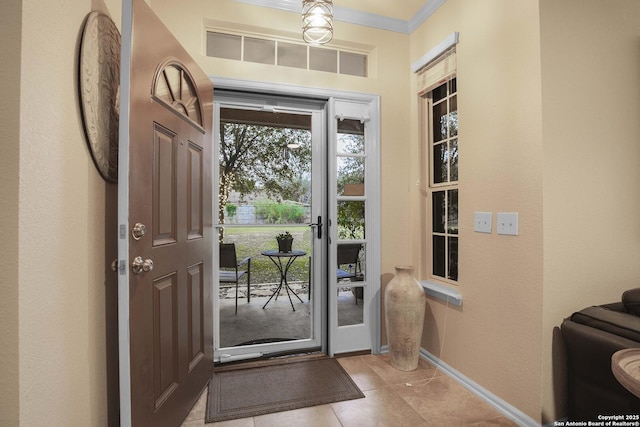 doorway with crown molding and light tile patterned floors