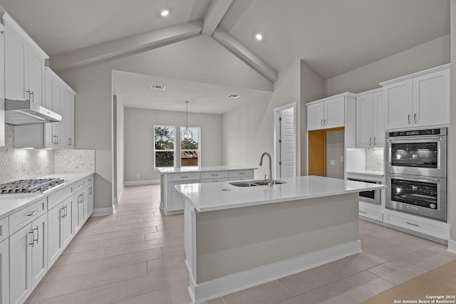 kitchen with sink, appliances with stainless steel finishes, a kitchen island with sink, white cabinetry, and decorative light fixtures