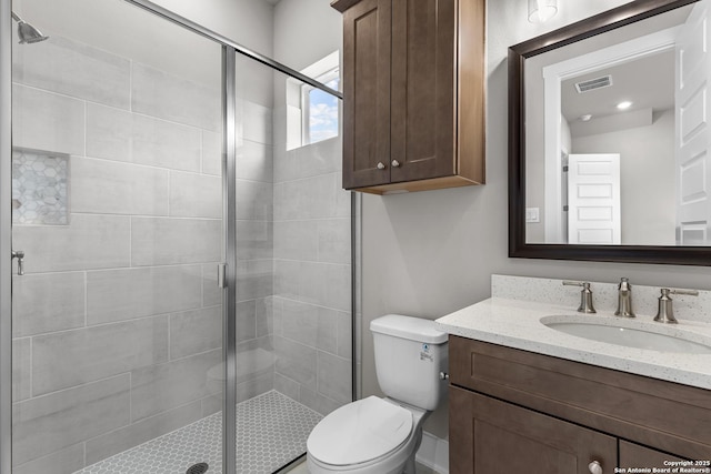 bathroom featuring a shower with door, vanity, and toilet