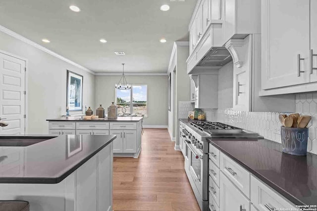 kitchen featuring sink, a breakfast bar, high end stainless steel range oven, white cabinetry, and hanging light fixtures