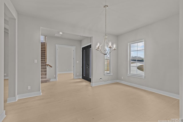 unfurnished dining area with a chandelier and light wood-type flooring