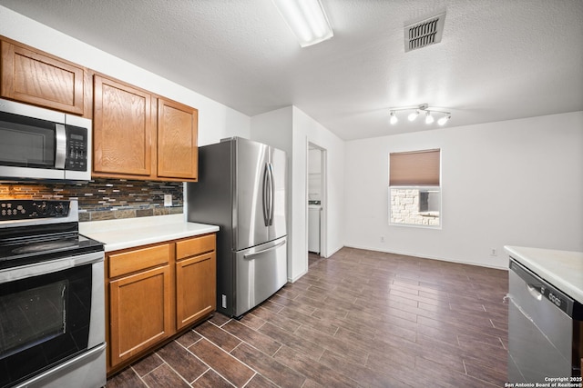 kitchen with appliances with stainless steel finishes, a textured ceiling, and tasteful backsplash