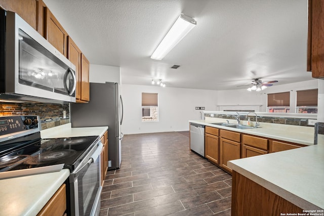 kitchen with ceiling fan, sink, stainless steel appliances, tasteful backsplash, and a textured ceiling