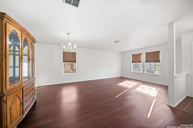 unfurnished living room featuring dark wood-type flooring and a chandelier