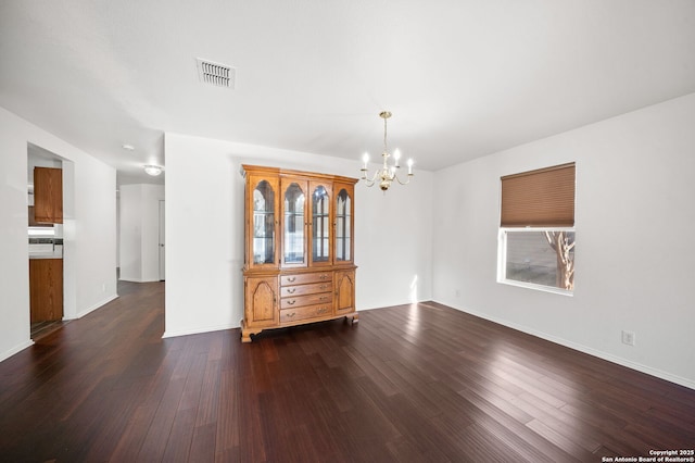 unfurnished dining area with a chandelier and dark wood-type flooring