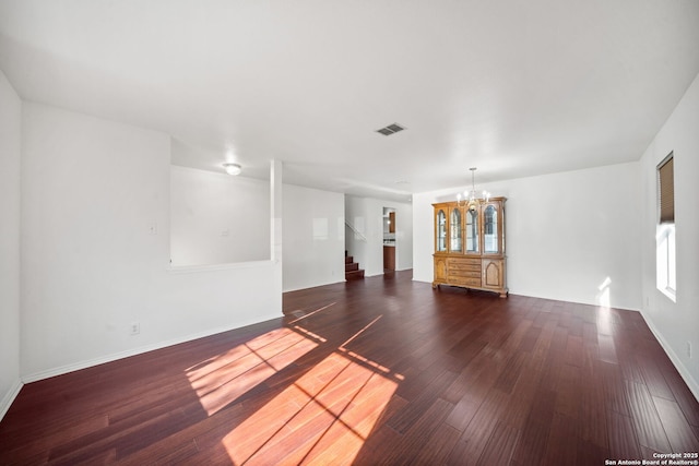 empty room with an inviting chandelier and dark wood-type flooring