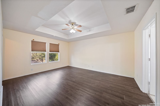 unfurnished room featuring ceiling fan, dark wood-type flooring, and a tray ceiling