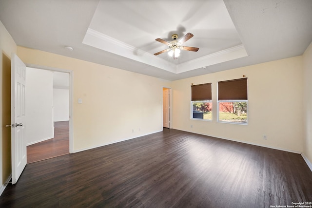 spare room featuring dark hardwood / wood-style floors, ceiling fan, and a raised ceiling