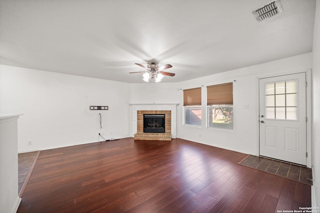 unfurnished living room featuring a fireplace, ceiling fan, and dark wood-type flooring