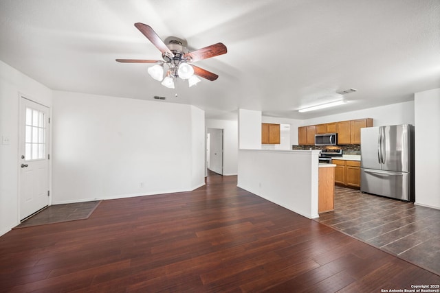 kitchen featuring decorative backsplash, stainless steel appliances, ceiling fan, and dark wood-type flooring