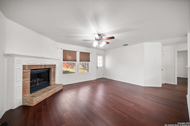 unfurnished living room with dark hardwood / wood-style flooring, a brick fireplace, and ceiling fan