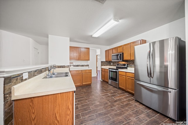 kitchen featuring backsplash, sink, kitchen peninsula, and stainless steel appliances