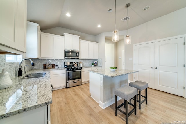 kitchen with white cabinetry, a center island, sink, stainless steel appliances, and lofted ceiling