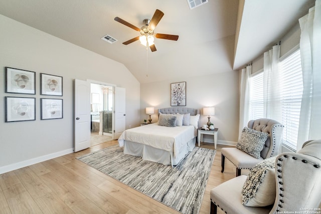 bedroom with ceiling fan, light wood-type flooring, lofted ceiling, and connected bathroom