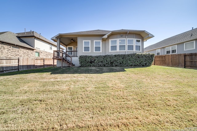 rear view of house featuring ceiling fan and a yard