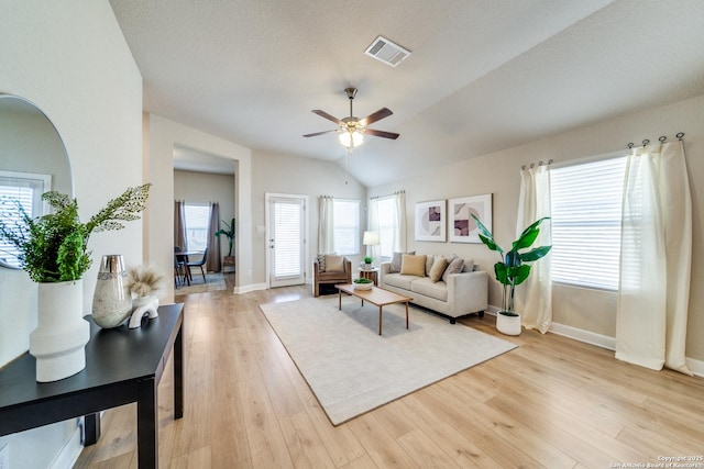 living room with ceiling fan, plenty of natural light, light hardwood / wood-style floors, and lofted ceiling