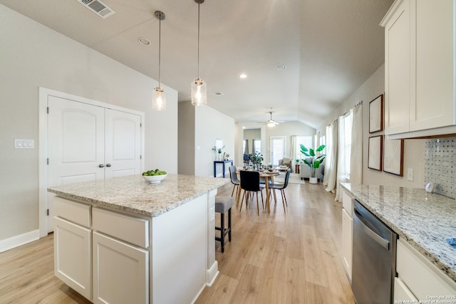 kitchen featuring dishwasher, white cabinets, ceiling fan, a kitchen island, and light stone counters