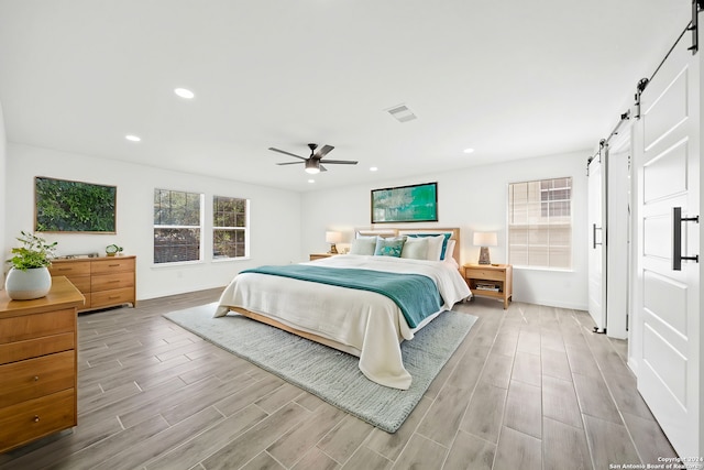 bedroom featuring ceiling fan and a barn door