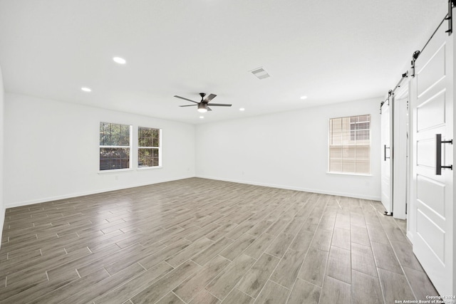 empty room with ceiling fan and a barn door