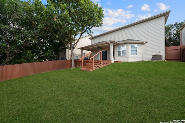 rear view of house with central air condition unit, a yard, and ceiling fan