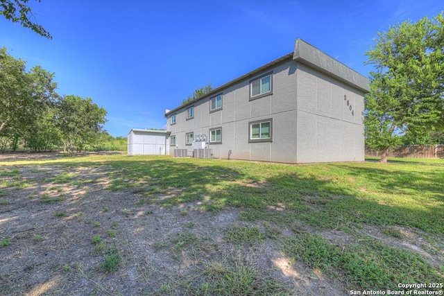 back of house featuring central AC unit and a yard