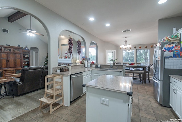 kitchen featuring stainless steel appliances, a kitchen island, sink, decorative light fixtures, and white cabinetry