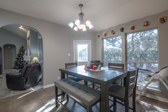 tiled dining room featuring vaulted ceiling and an inviting chandelier