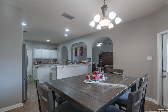 tiled dining room featuring ceiling fan with notable chandelier