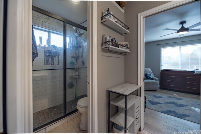 bathroom with an enclosed shower, ceiling fan, toilet, and hardwood / wood-style floors