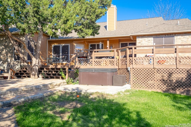 back of house with a yard, a hot tub, and a deck