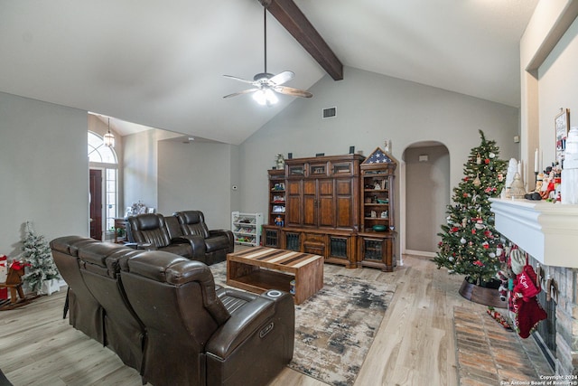 living room with ceiling fan, beam ceiling, high vaulted ceiling, light hardwood / wood-style flooring, and a fireplace