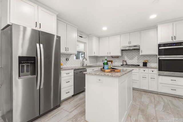 kitchen featuring white cabinets, sink, a kitchen island, light stone counters, and stainless steel appliances