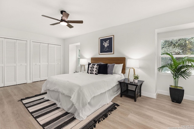 bedroom featuring ceiling fan, light wood-type flooring, and multiple closets