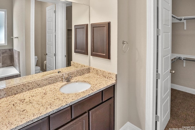 bathroom with a bathing tub, vanity, and toilet