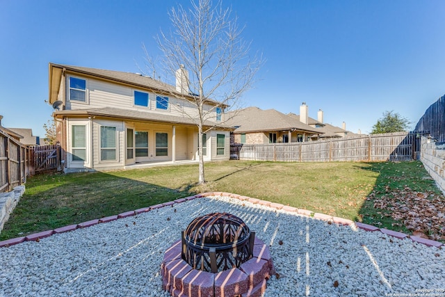 rear view of property with a fire pit and a yard