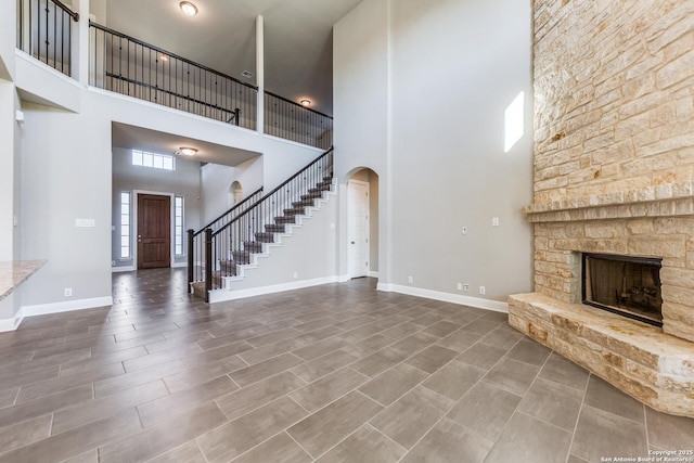 unfurnished living room featuring a stone fireplace and a towering ceiling