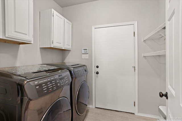 washroom featuring light hardwood / wood-style floors, cabinets, and washing machine and clothes dryer