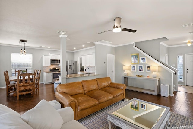 living room featuring ceiling fan with notable chandelier, dark hardwood / wood-style floors, ornamental molding, and sink