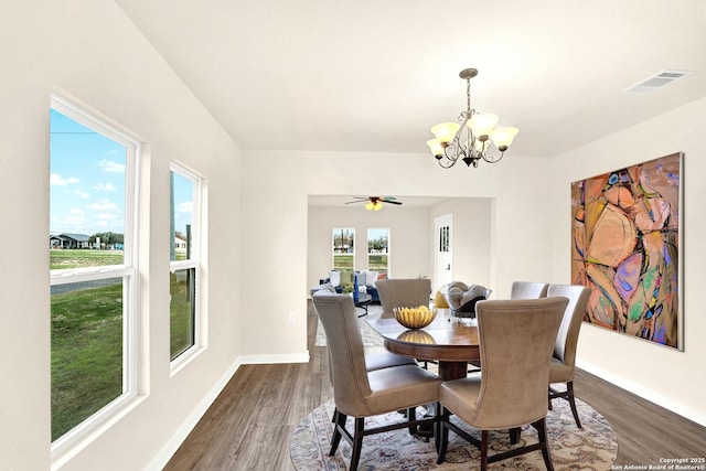 dining room with dark wood-type flooring and ceiling fan with notable chandelier